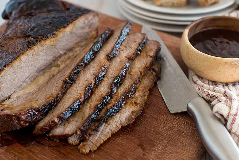 Instant Pot brisket sliced on a cutting board with bbq sauce.