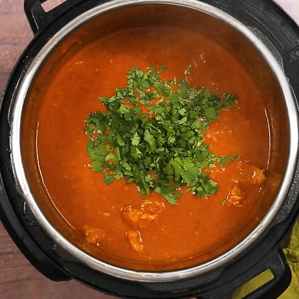 Indian Butter Chicken inside the cooking pot, topped with cilantro