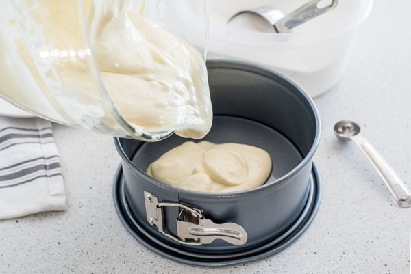 Pouring cheesecake in a springform pan to make a crustless Instant Pot cheesecake to use for cheesecake pops.