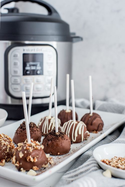 Chocolate dipped cheesecake bites plated in front of an Instant Pot.
