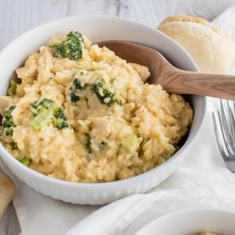 photo of Instant Pot cheesy chicken and broccoli casserole in a white bowl with a wooden spoon.