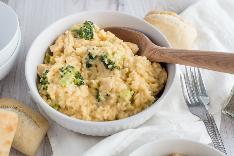 photo of Instant Pot cheesy chicken and broccoli casserole in a white bowl with a wooden spoon.