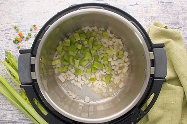 Overhead of Instant Pot with diced celery and onions to make homemade chicken pot pie filling.
