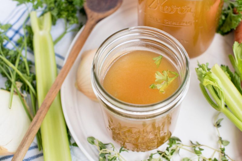 jar of instant pot chicken stock with fresh celery on a white platter 