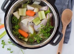 overhead of an instant pot cooking chicken stock with carrots, celery, onions and fresh herbs