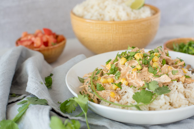 Close up of Instant Pot creamy chipotle chicken served over white rice and garnished with fresh cilantro and served in a white bowl.
