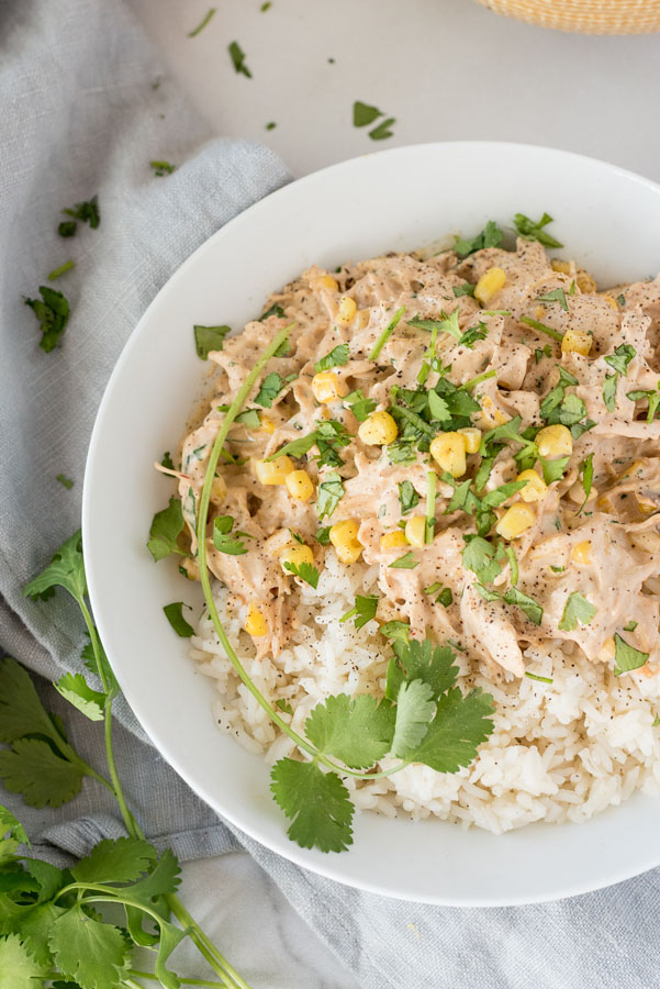 Instant Pot creamy chipotle chicken served over white rice, and garnished with cilantro, served in a white bowl