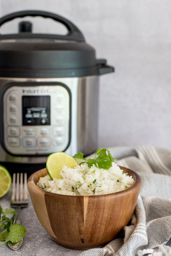 Bowl of cilantro lime white rice in front of an electric instant pot pressure cooker