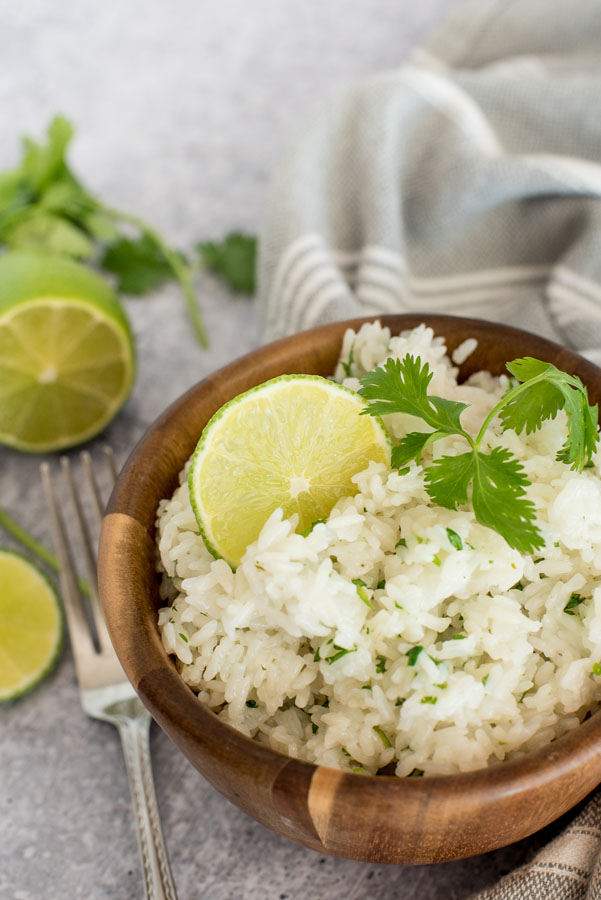 Instant pot cilantro lime white rice in a wooden bowl topped with fresh lime and cilantro