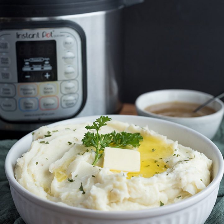 The Best Instant Pot Mashed Potatoes Recipe, featuring a white bowl of mashed potatoes with butter on top and an Instant Pot in the background