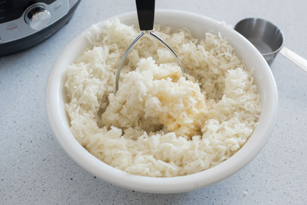 Step for Instant Pot Mashed Potatoes: Finish off by using a potato masher to mix the liquids into the riced potatoes
