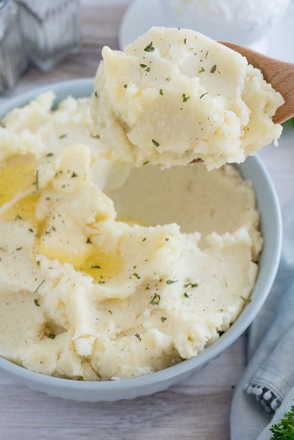 A thick scoop of Instant Pot mashed potatoes, garnished with dried parsley and melted butter