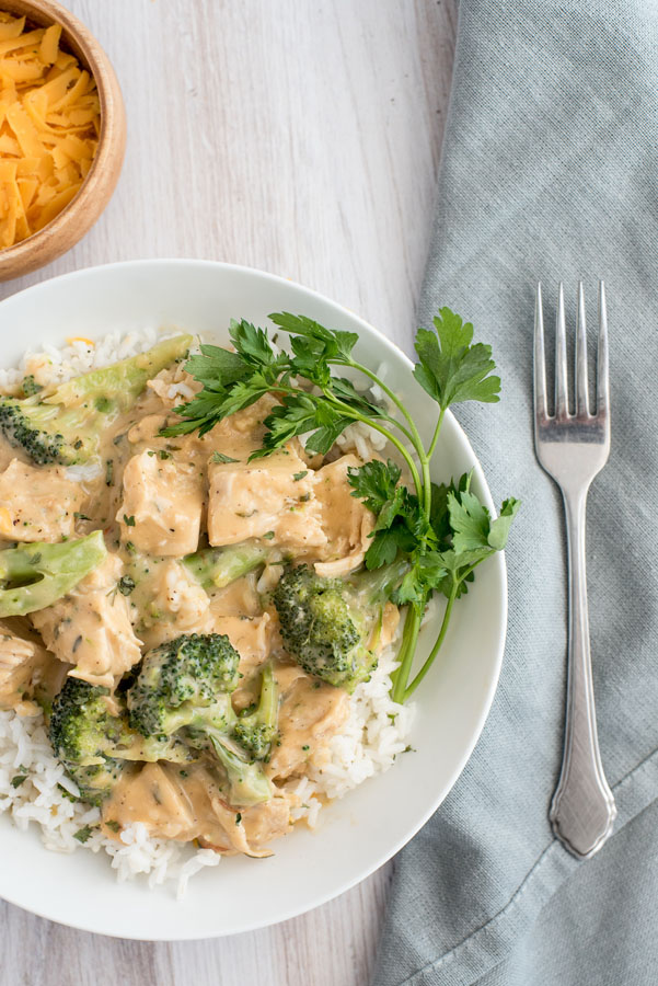 Creamy chicken and broccoli over rice on a white plate with fork on the side