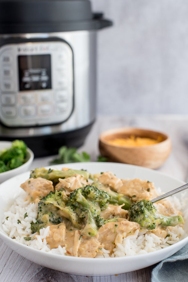 A bowl of chicken and broccoli over rice in front of an Instant Pot