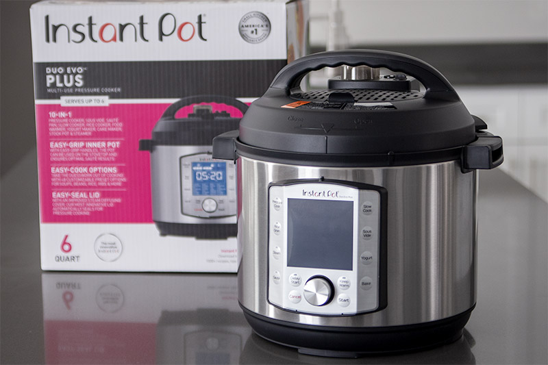 Instant Pot Duo Evo Plus sitting on a gray countertop with the InstaPot Evo packaging in the background.