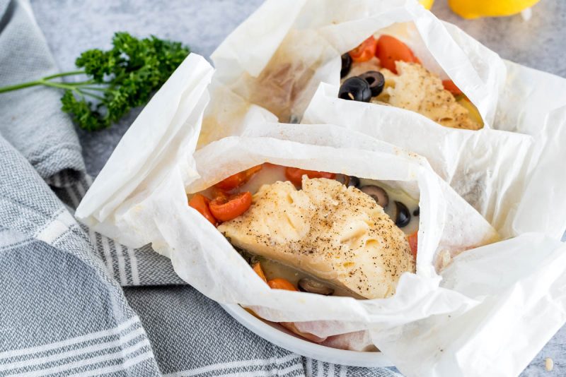 two parchment paper packets with fish fillets 