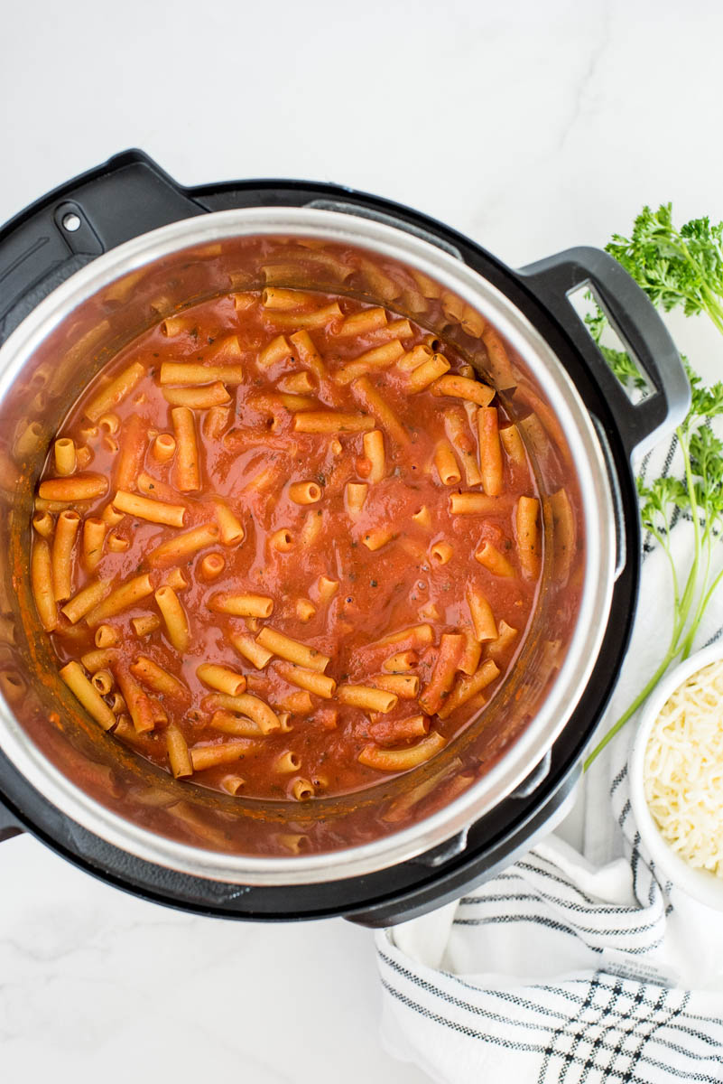 An overhead shot looking into an Instant Pot filled with cooked ziti and marinara sauce, before adding the alfredo sauce