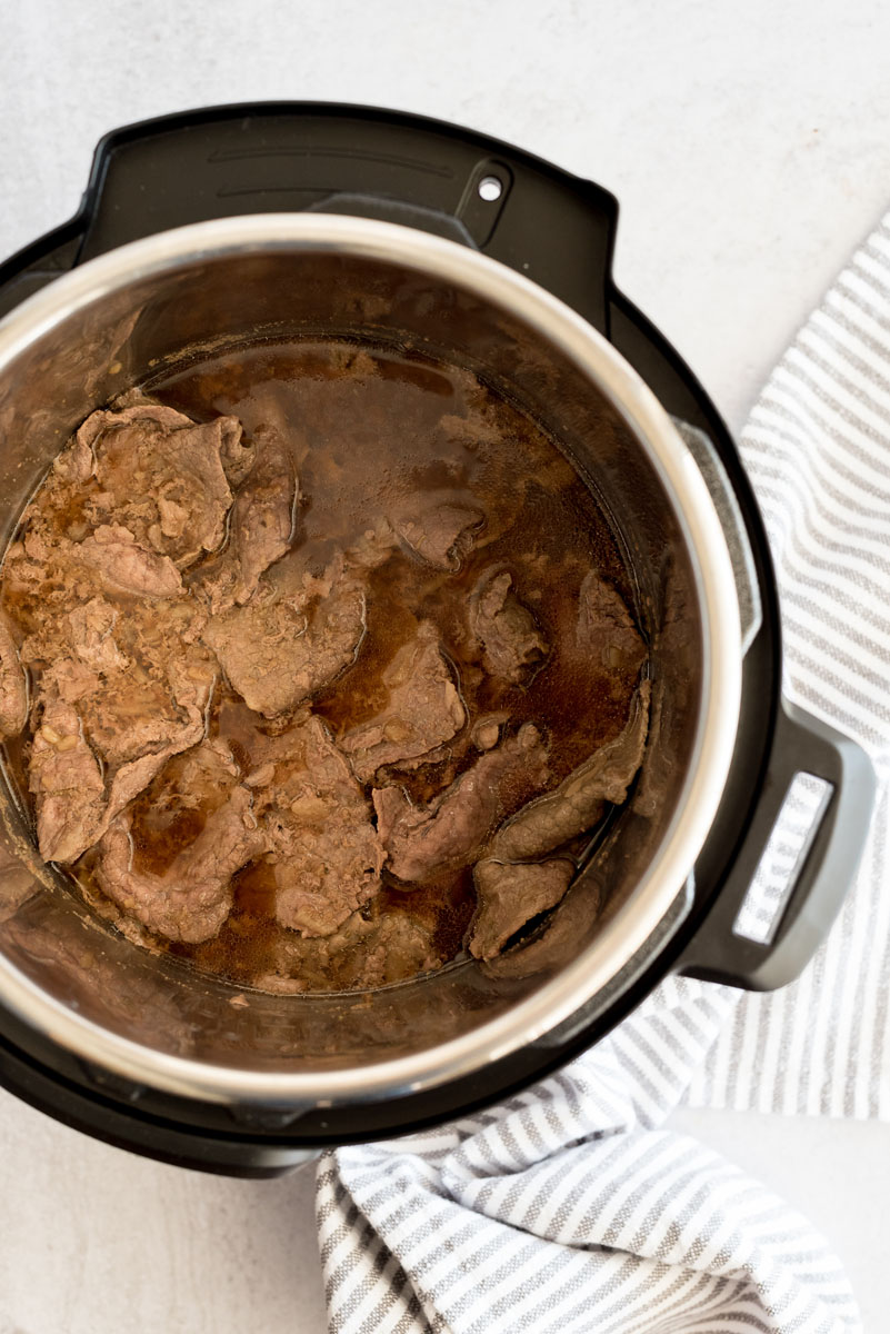 Overhead shot of sliced beef cooked in au jus inside an Instant Pot.