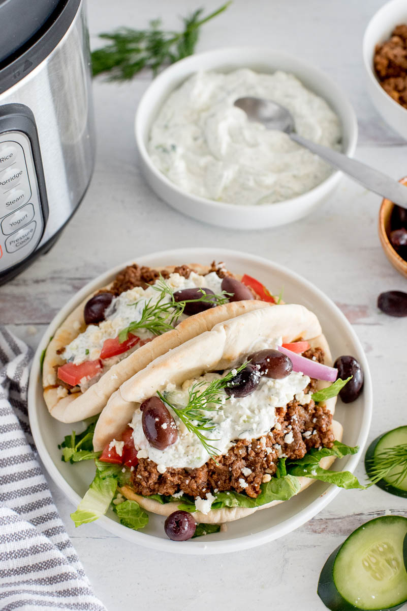 two greek beef tacos in front of an instant pot