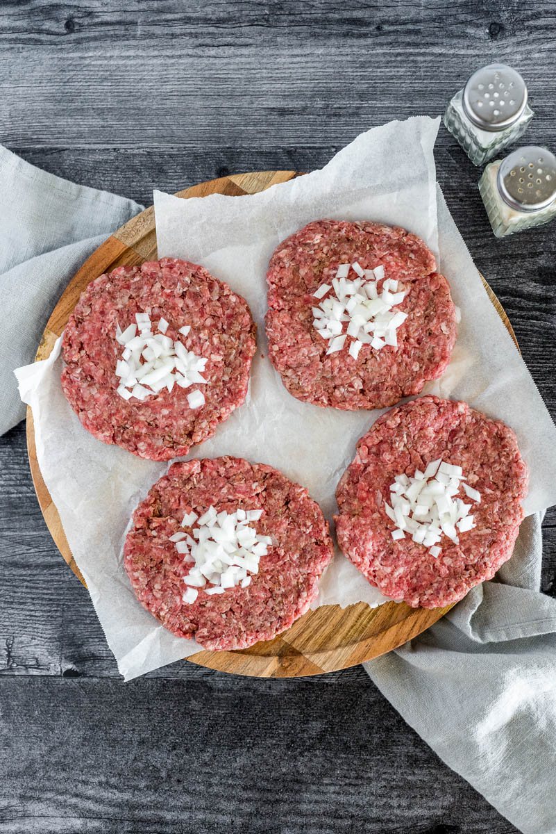 four burger patties with diced sweet onion in the center