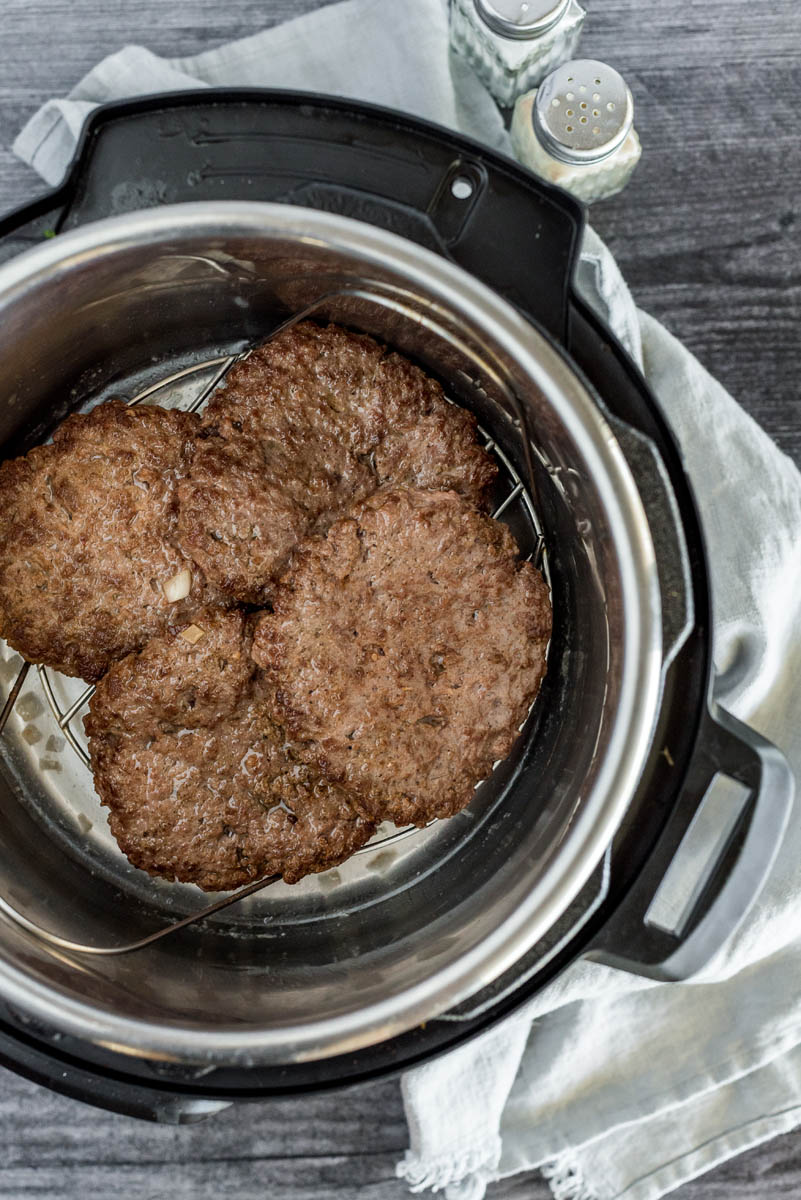 overhead of an instant pot with four hamburgers inside on a wire rack