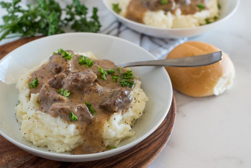 white bowl with swedish kalops beef stew over mashed potatoes