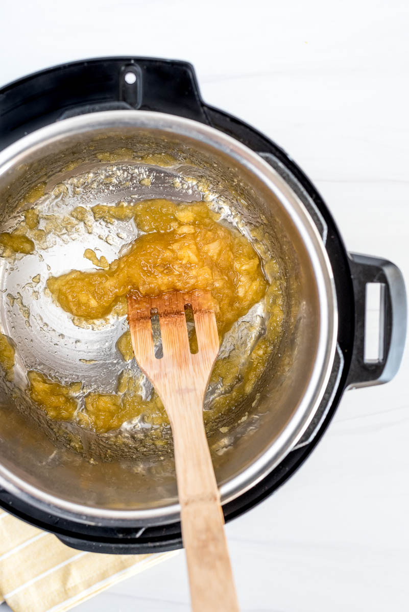 An overhead shot of the pineapple sauce stirring around by a wooden spoon