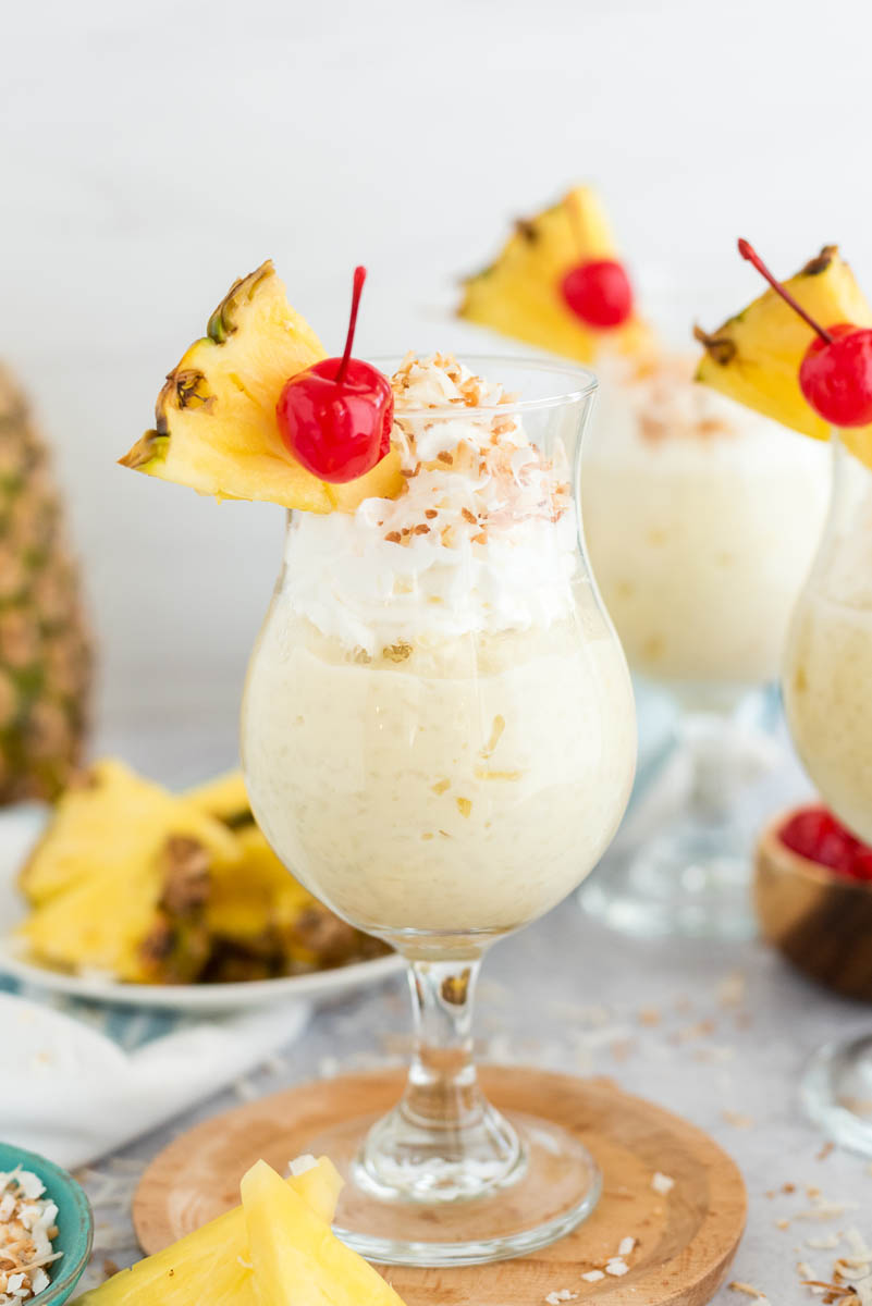 several glasses of coconut pudding with fresh fruit and whipped cream on top