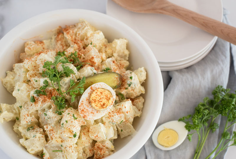 overhead of a white serving bowl with instant pot potato salad with hard-cooked eggs