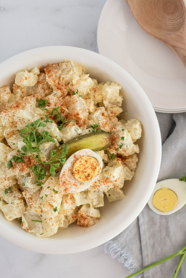 white bowl of quick instant pot potato salad with mayonnaise dressing and hard boiled eggs