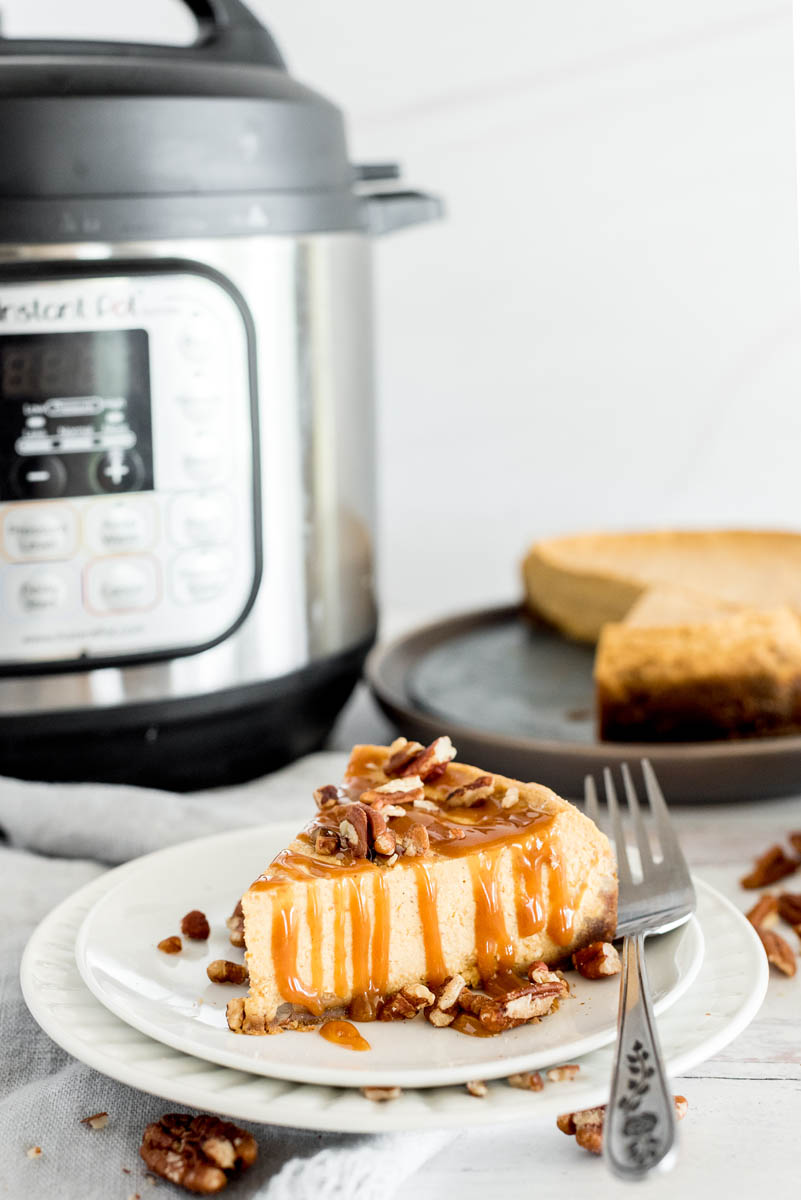 slice of pumpkin cheesecake in front of an instant pot