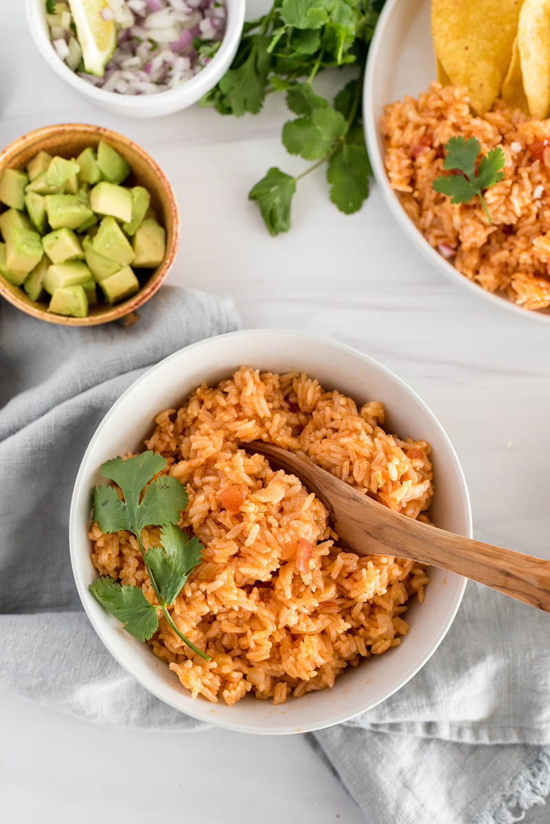 white bowl with spanish rice and green garnishes