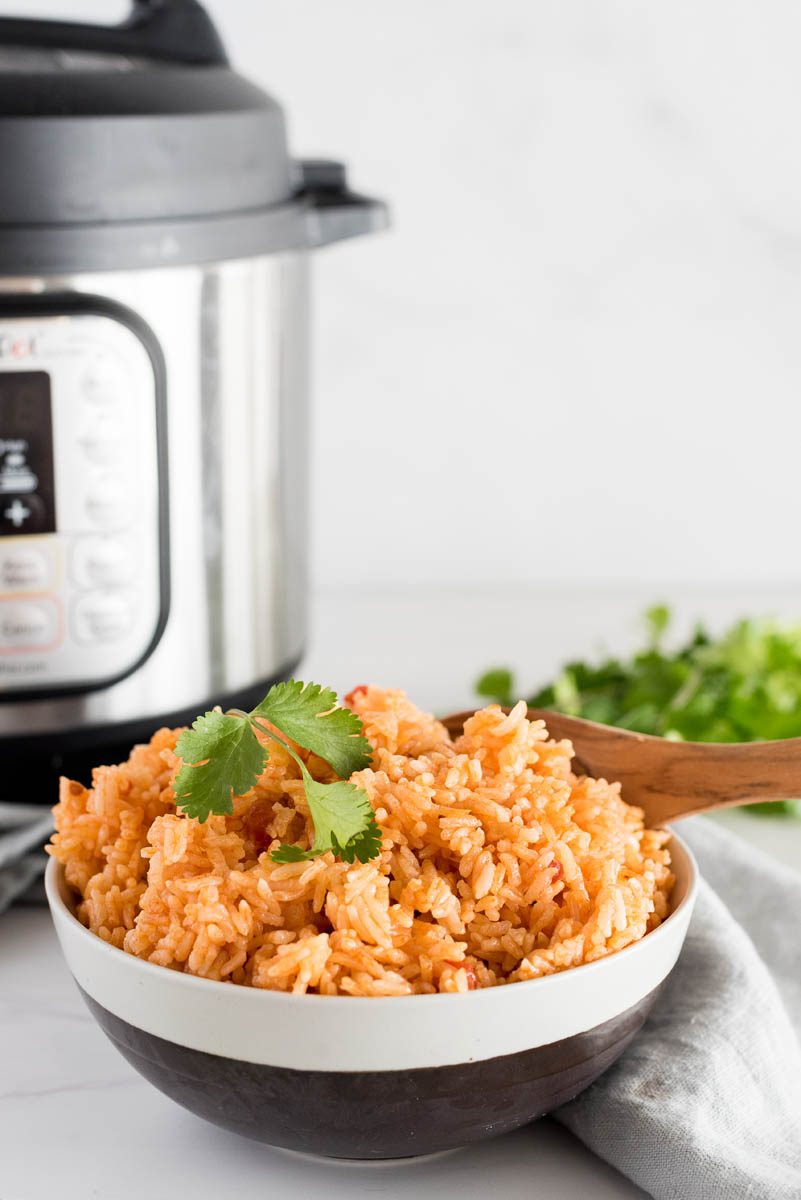 bowl of spanish rice with cilantro in front of an instant pot