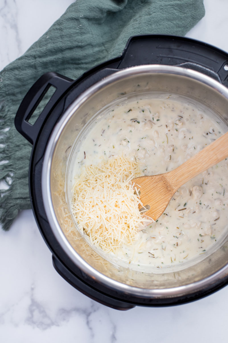 making alfredo cheese sauce with rosemary for white chicken lasagna in an electric pressure cooker
