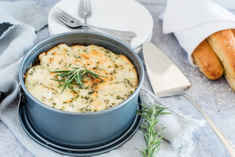 freshly made Instant pot white chicken alfredo lasagna in a round springform pan with a sprig of rosemary and breadsticks
