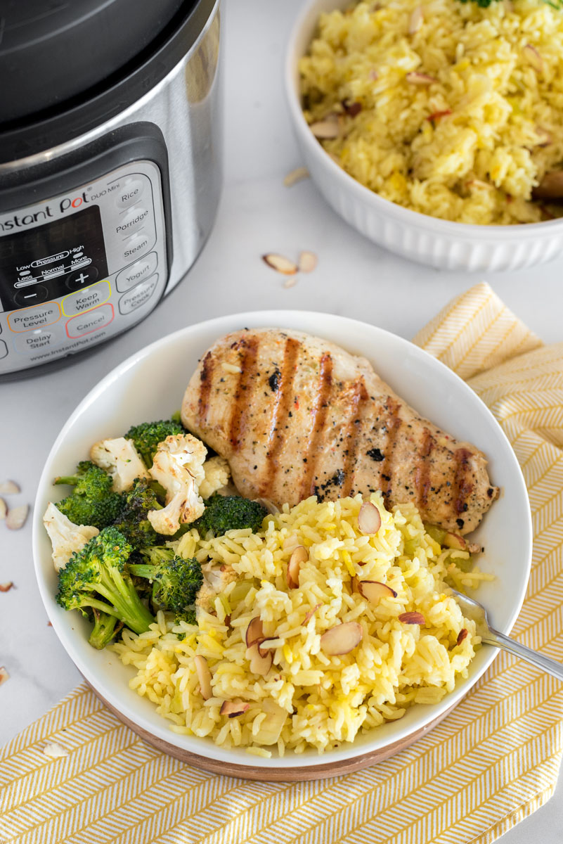 bowl of saffron almond irce pilaf with grilled chicken breast and broccoli