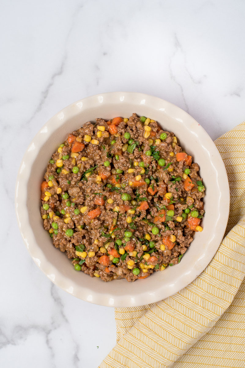 Overhead shot of the meat mixture with peas and carrots in a baking dish for Instant Pot shepherds pie.