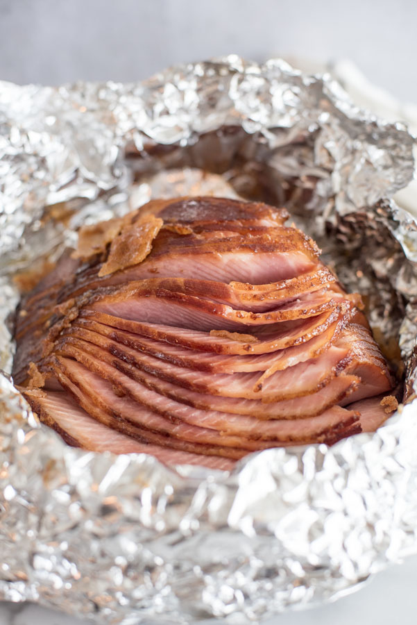 Close up on spiral cut warmed honey baked ham in tin foil from the Instant Pot.
