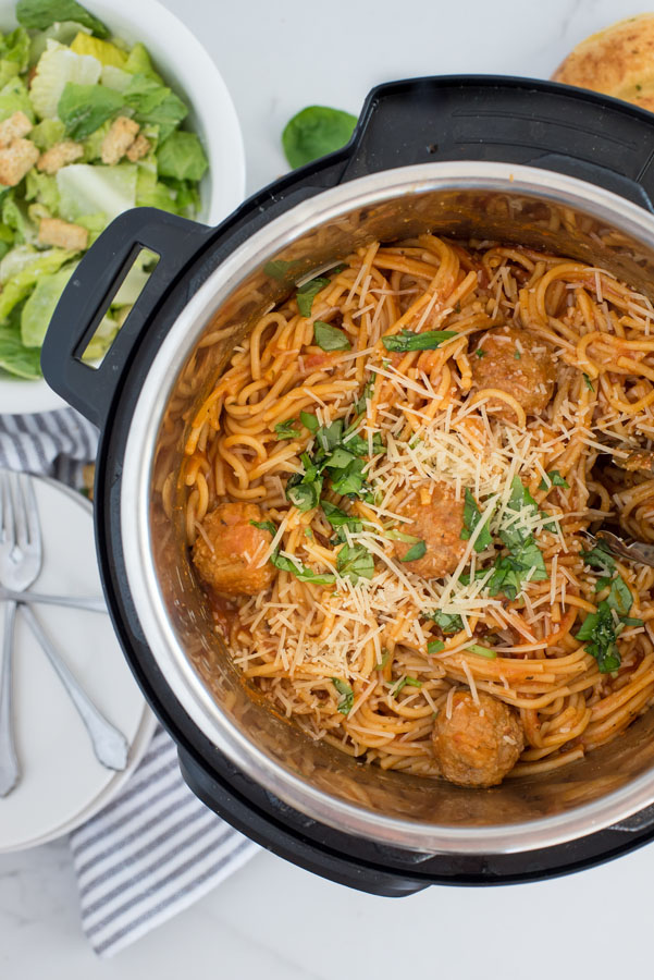 overhead shot of Instant Pot spaghetti and meatballs inside an instant pot, with a green salad on the side