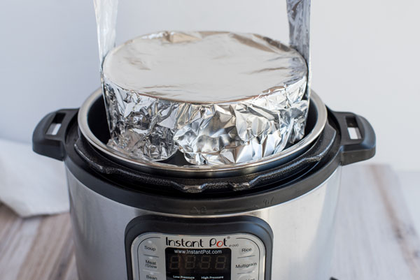 Using a foil sling to remove the pot with hot spinach artichoke dip cooked in an Instant Pot.