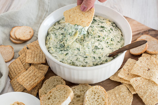 A chip dipping into Instant Pot spinach artichoke dip.