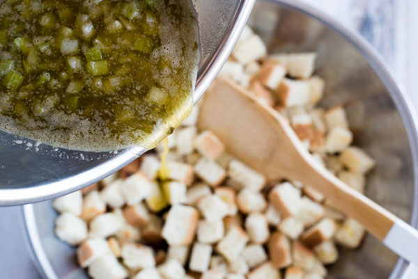 Butter, broth, and seasonings being poured on top of the cubed bread for Instant Pot White Bread Dressing