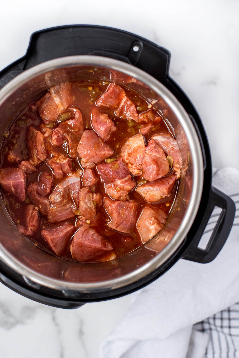 overhead of an instant pot with pieces of pork cooking in a red sauce
