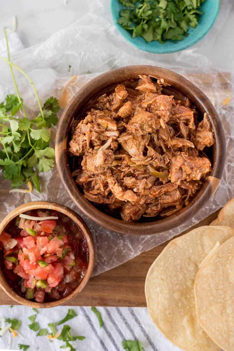 overhead of a bowl of sweet pork and a bowl of tomatoes salsa with crispy tortillas
