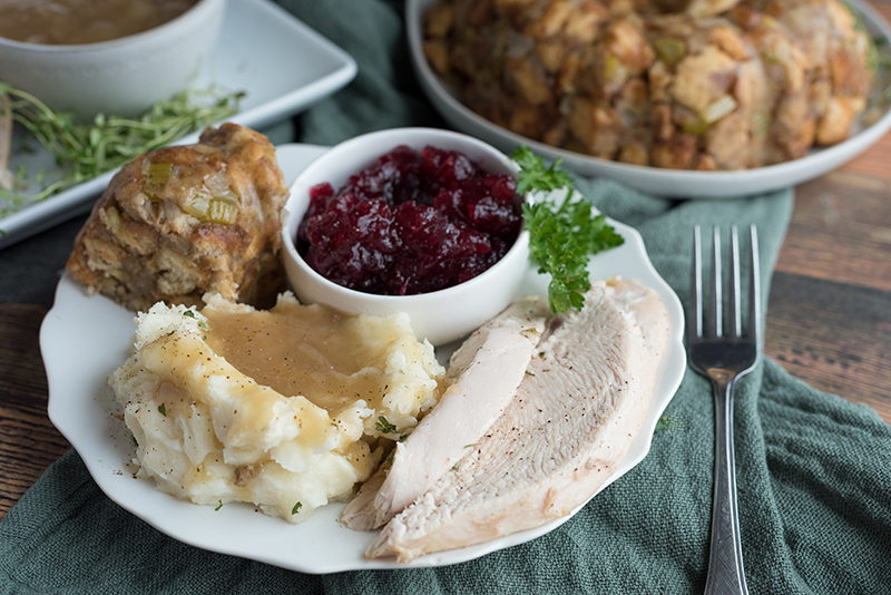 A plate of sliced turkey, mashed potatoes, stuffing and cranberry sauce