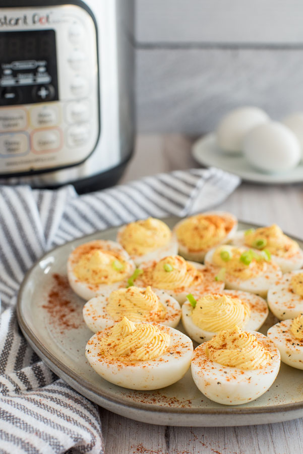 Grey ceramic plate filled with a dozen Instant Pot deviled eggs filled with homemade deviled egg filling made with flavored mustard, paprika and scallions.