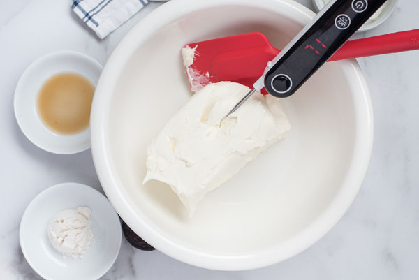 Checking the cream cheese for a strawberry cheesecake recipe with a thermometer to make sure that it is room temperature.