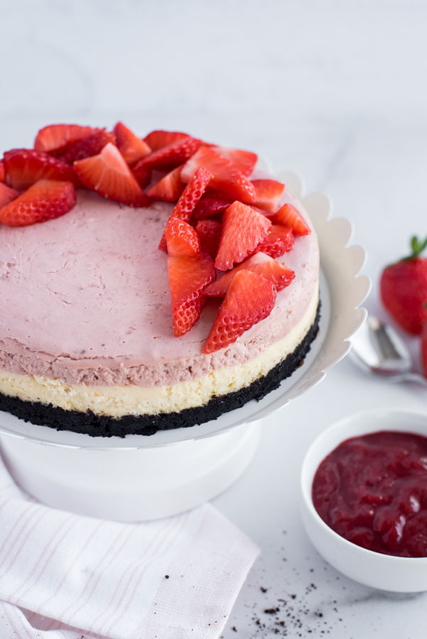 Instant Pot layered strawberry cheesecake on a platter with strawberries on top.