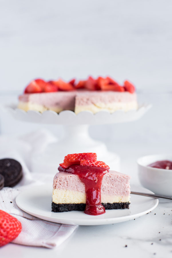 Layered strawberry cheesecake sliced, and plated to serve.