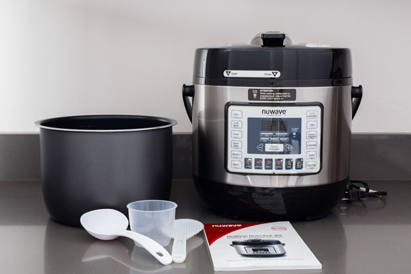NuWave Pressure Cooker with a non-stick inner pot, ladel, rice scoop, measuring cup, and manual.